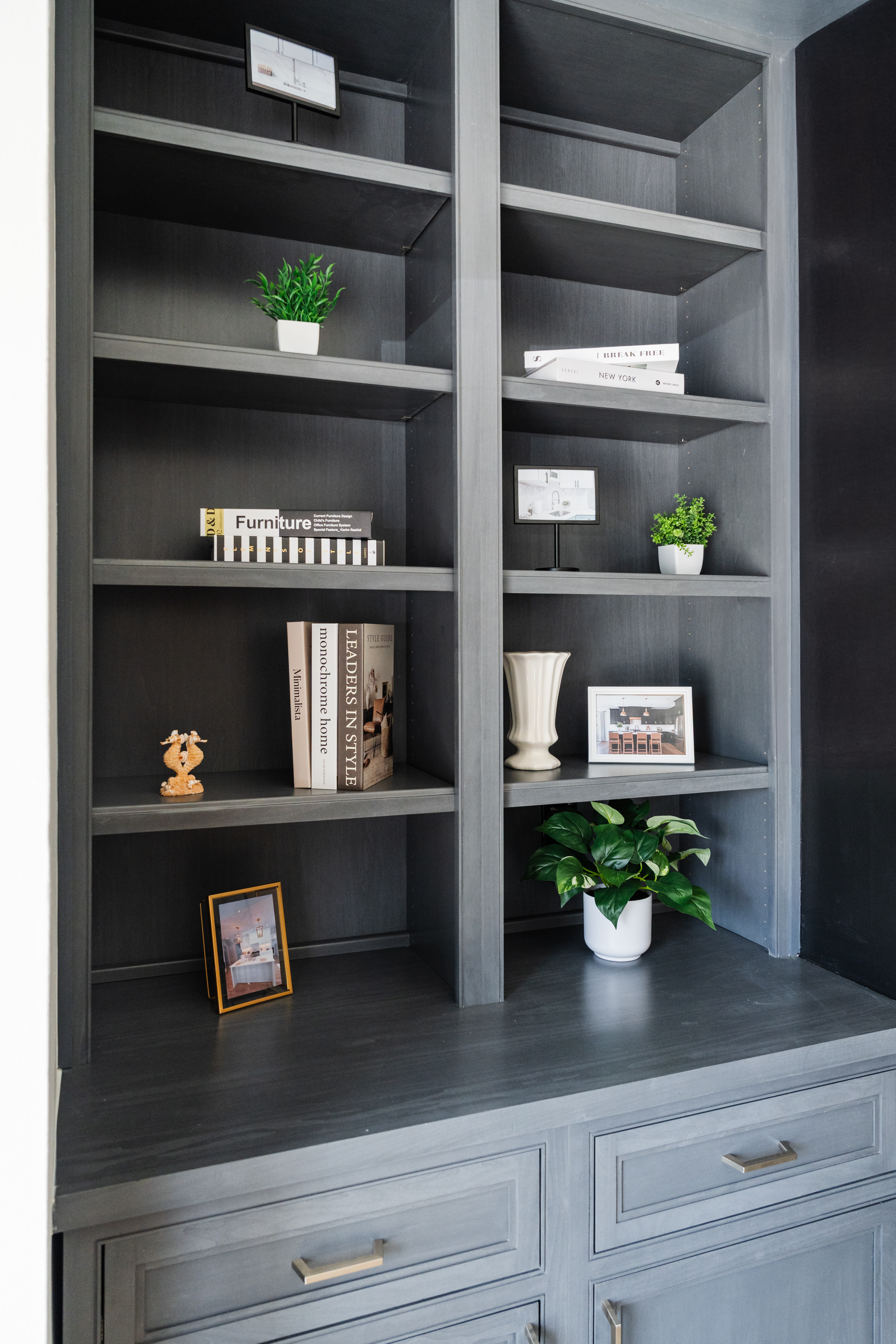 A built-in dark gray bookshelf with decorative items, including books, small framed photos, and potted plants, adds a stylish touch—perfect inspiration for any DC remodeling project or kitchen remodeler seeking fresh ideas.