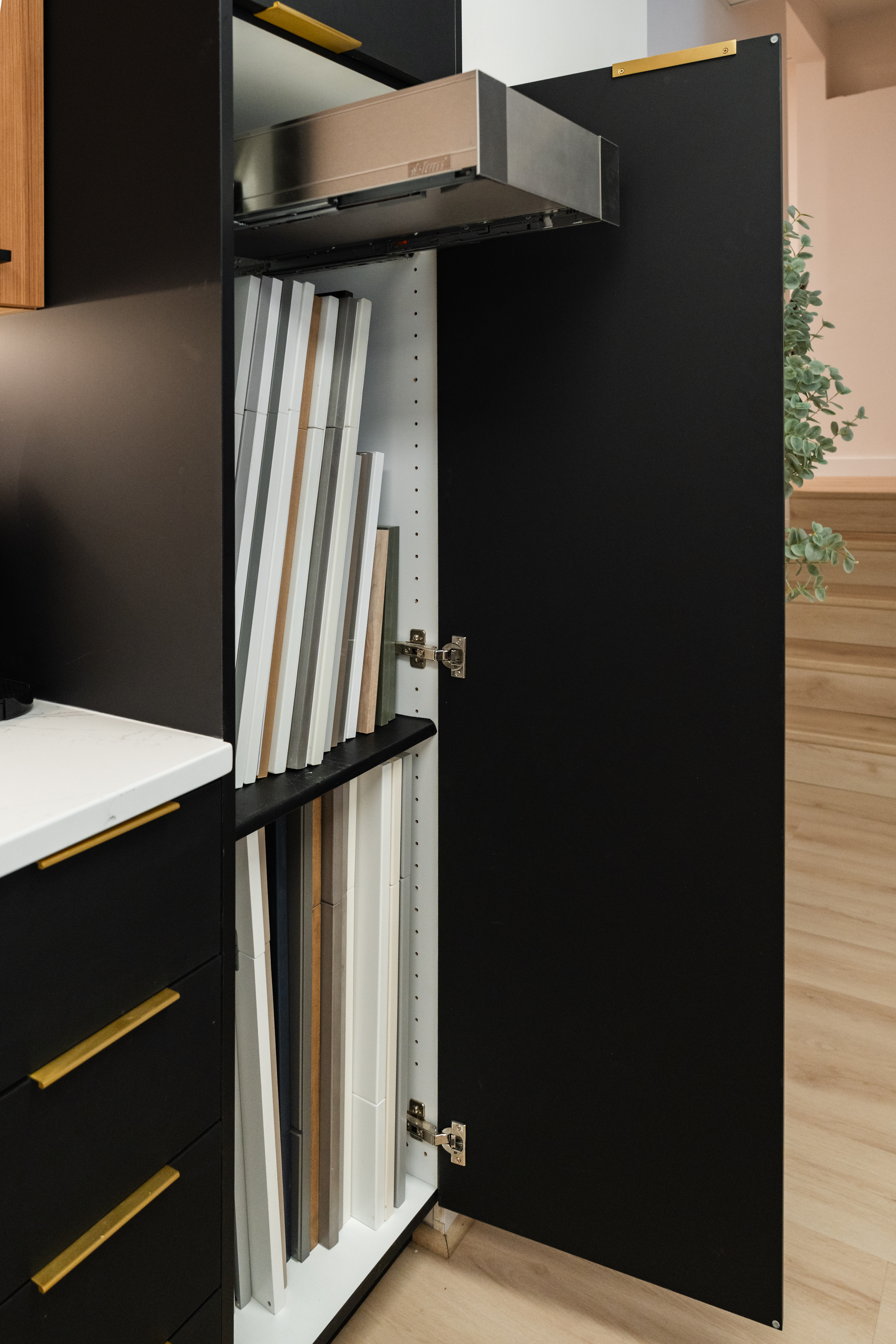 A tall black cabinet with an open door reveals shelves storing multiple cutting boards and baking sheets arranged vertically. Perfect for a modern kitchen, this design showcases the skill of a top Maryland kitchen remodeler.